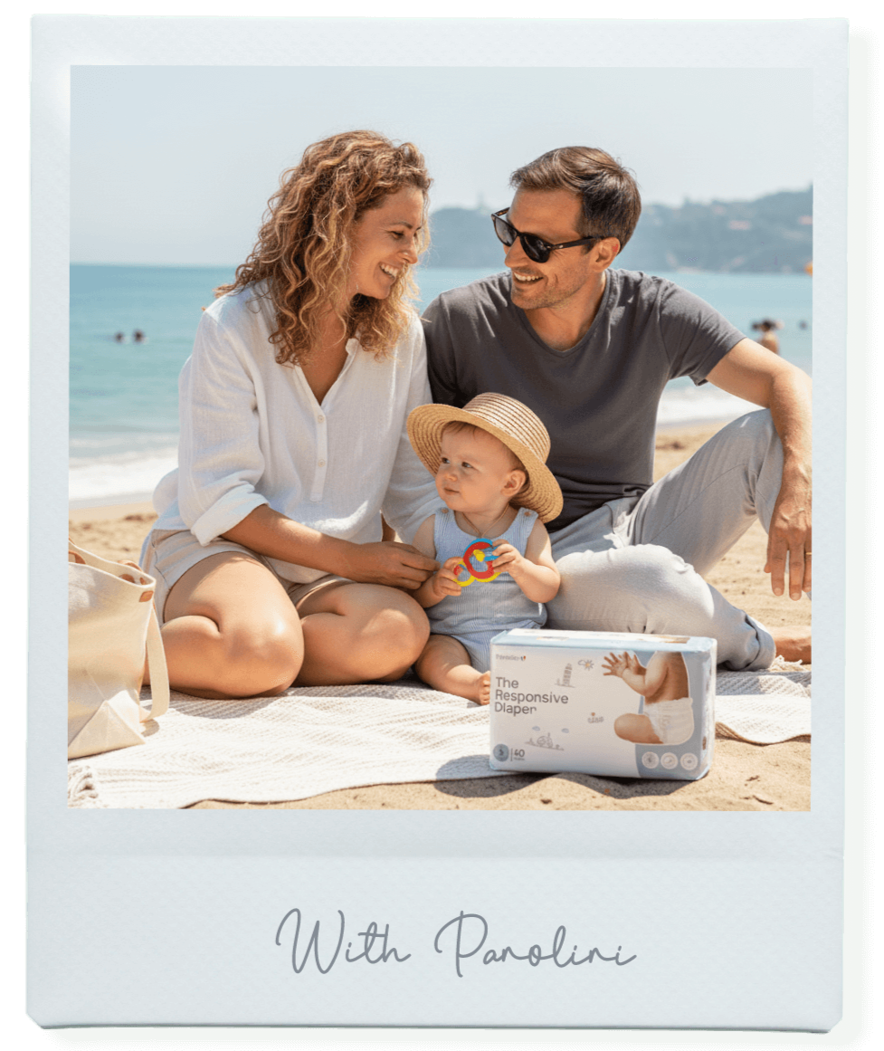 Family sitting on a beach with a baby and a box of Panolini diapers.